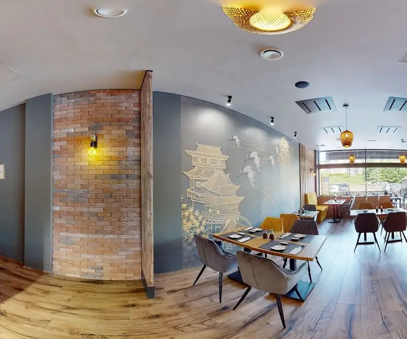 Sala z muralem z pagodą, ceglaną ścianą i stolikami